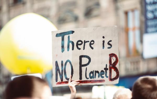 a sign being held above a crowd, it reads: 'There is no Planet B'