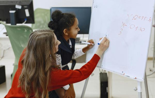 A teacher and student doing maths on a whiteboard
