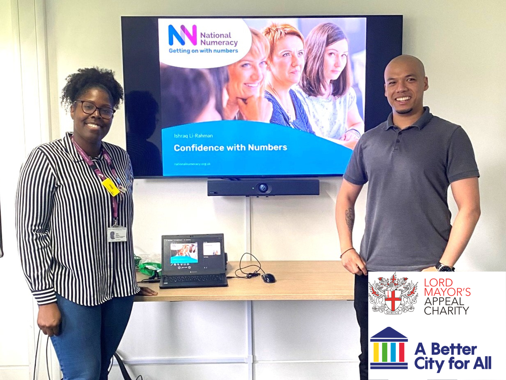 A number confidence building session with two smiling people in front of a screen