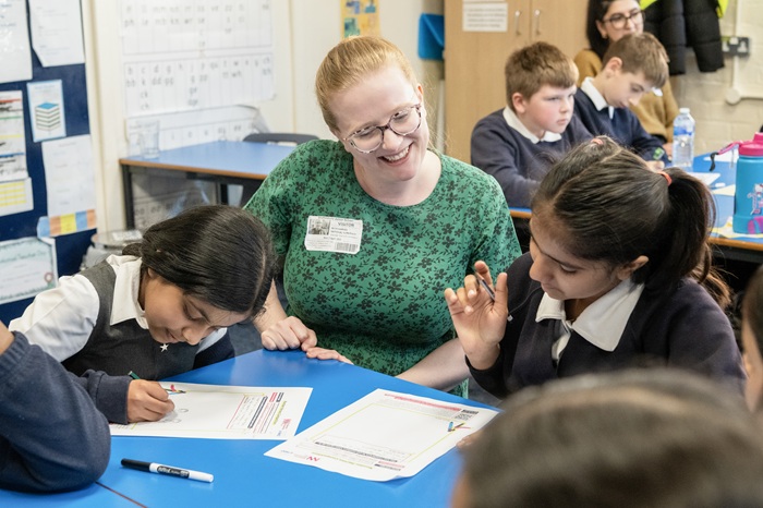 Smiling teacher sitting with pupils