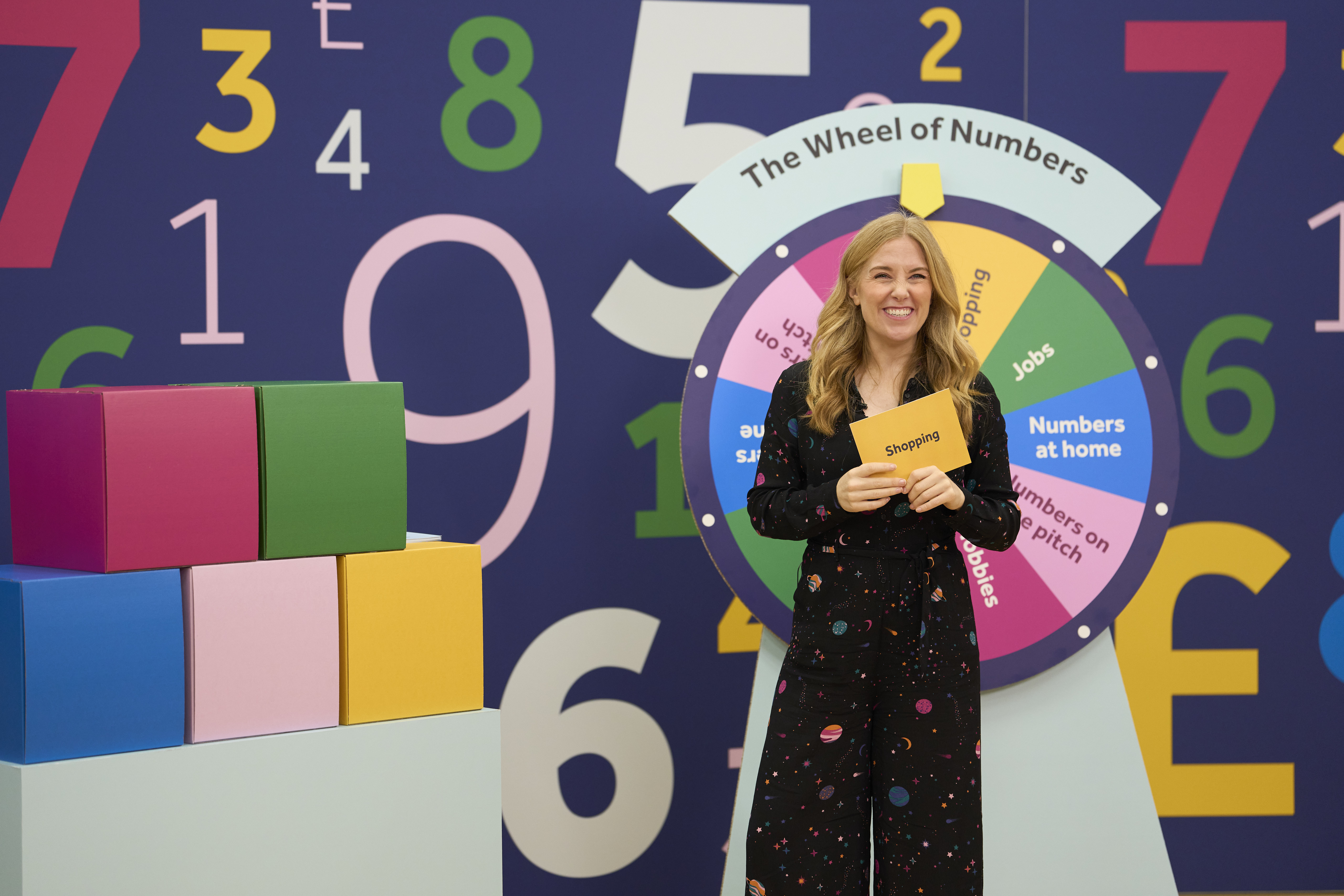 Maddie Moate smiling and standing in front of the Wheel of Numbers