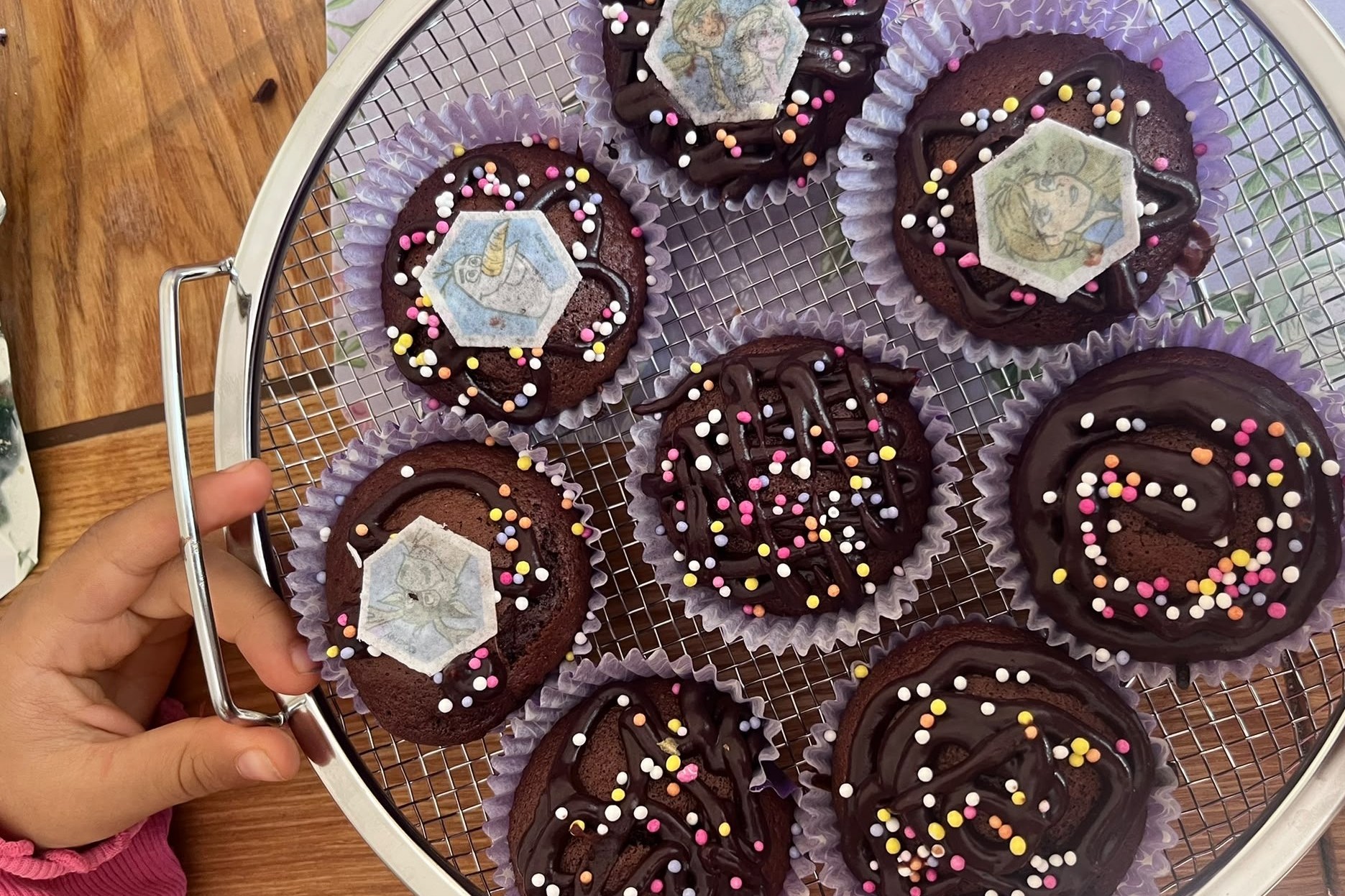 A tray of chocolate cupcakes decorated with chocolate icing and colourful sprinkles
