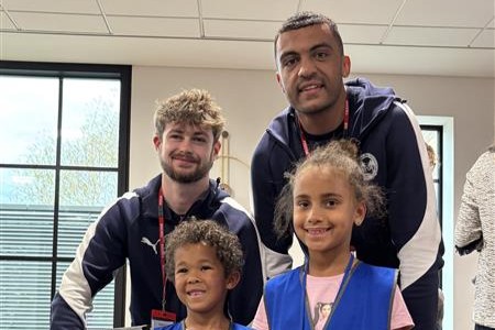 Peterborough United FC footballers David Okagbue and Cian Hayes pose for a photo with two children
