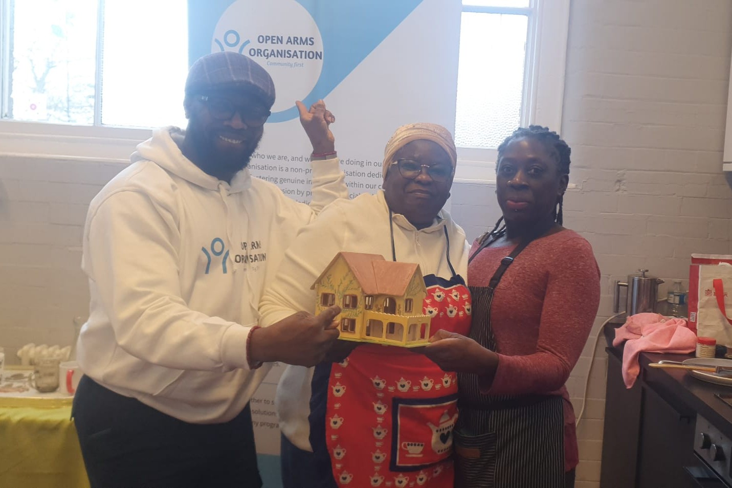 Three people holding a model of a house and smiling