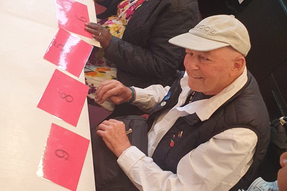 A person smiling and sitting at a table with numbered cards on it