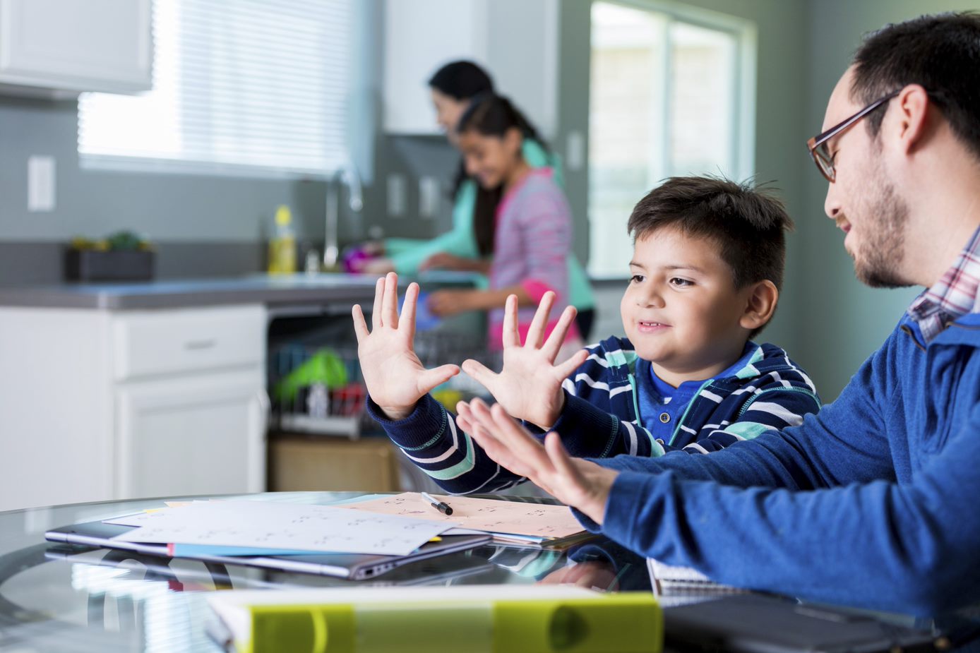 Photo of a parent next to a child who is counting with their fingers
