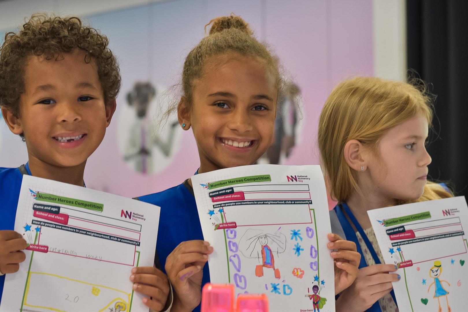 Children holding Number Heroes drawings