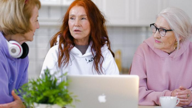 Photo of three women gathered around a laptop
