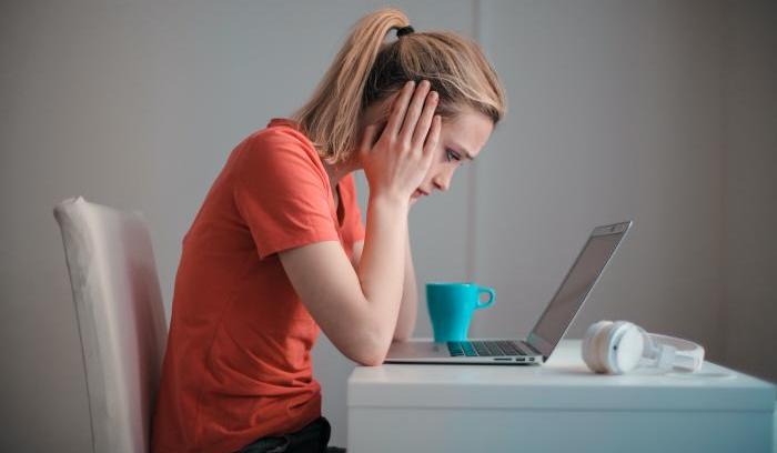 Woman looking despairingly at a laptop