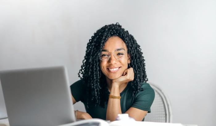 Young woman at looking past laptop smiling