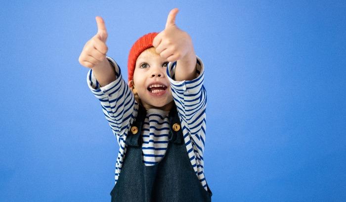 Young boy showing thumbs up on blue background