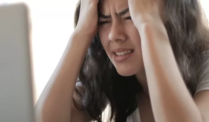 Stressed woman at laptop represents how some symptoms of maths anxiety can show up in our lives