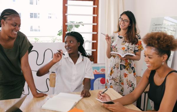 Stock image of adults around a table with a laptop