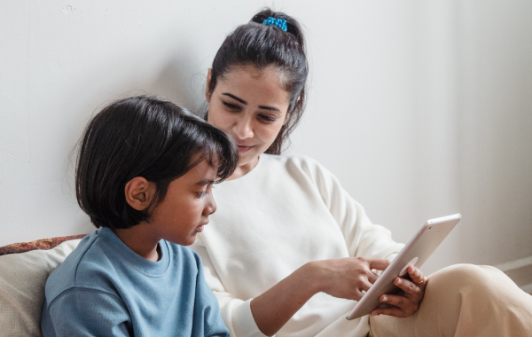 An adult showing a child something on a tablet