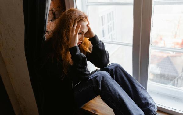 Anxious young woman sitting by a window