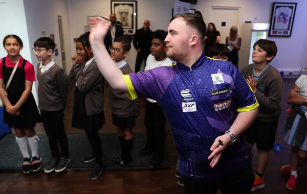 Darts player Luke Littler preparing to throw a dart