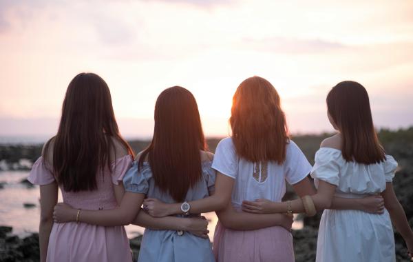 A view from behind of four women side by side looking into the distance