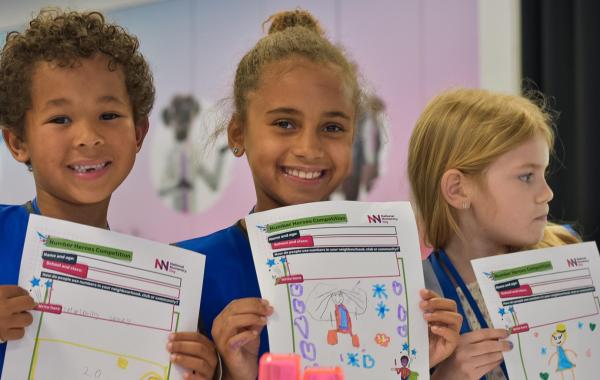 Three children hold up drawings they have done for National Numeracy's Number Heroes competition