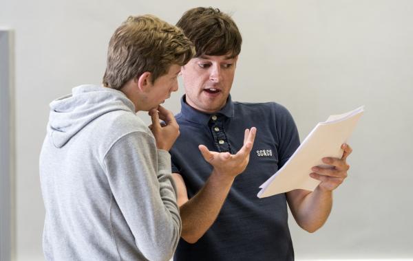 A curriculum leader holds some papers while talking to a pupil about their GCSE results
