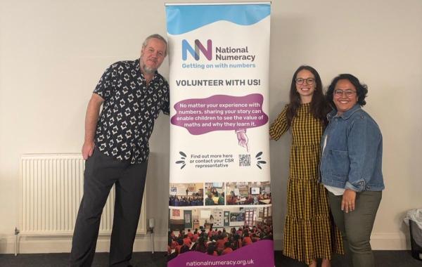 National Numeracy staff standing next to a National Numeracy banner and smiling