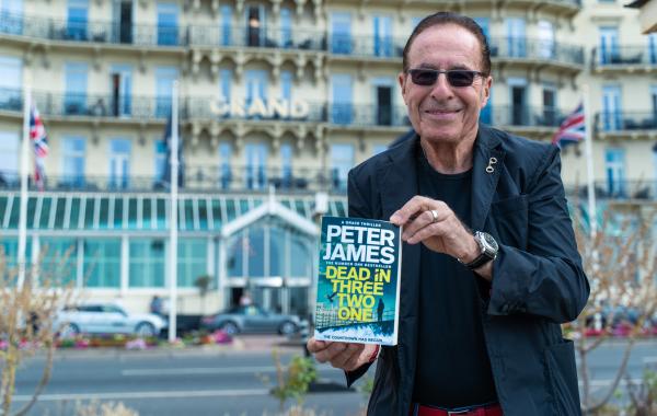 Author Peter James holding a copy of his book, Dead in Three Two One
