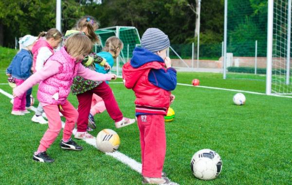 Group of young children scoring goals with footballs