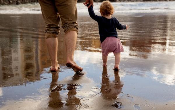 Adult and toddler walking together at the seaside