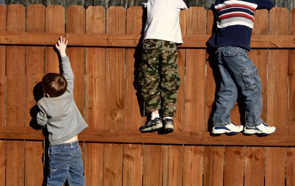 Three children looking over a fence - one needs a leg up