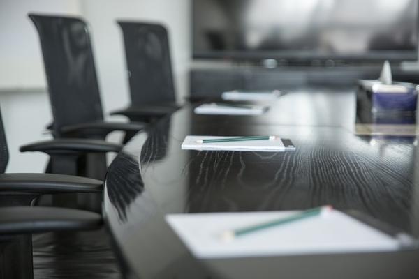 Photo of chairs around a table, with paper on the table, ready for a meeting