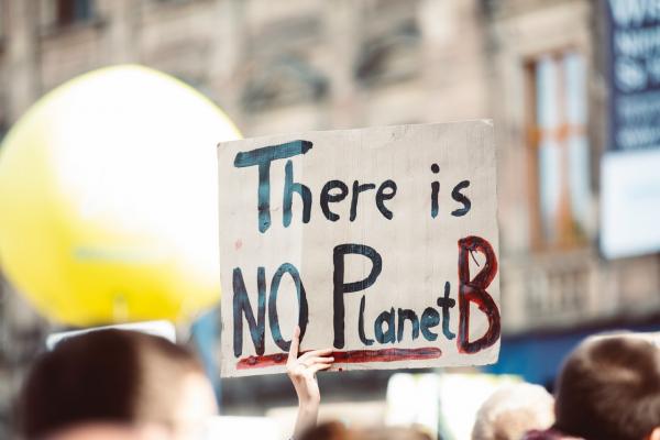 a sign being held above a crowd, it reads: 'There is no Planet B'