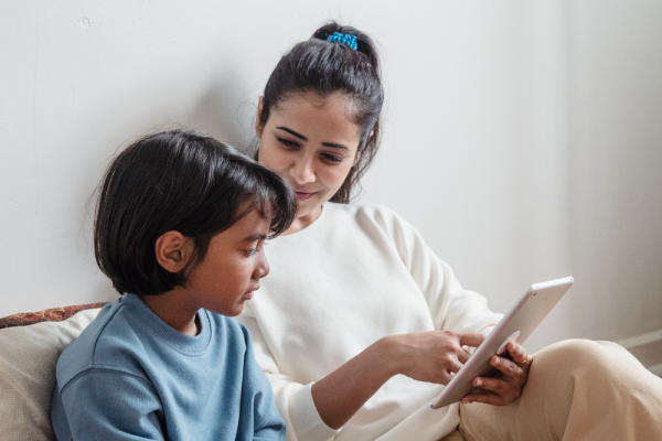 An adult showing a child something on a tablet