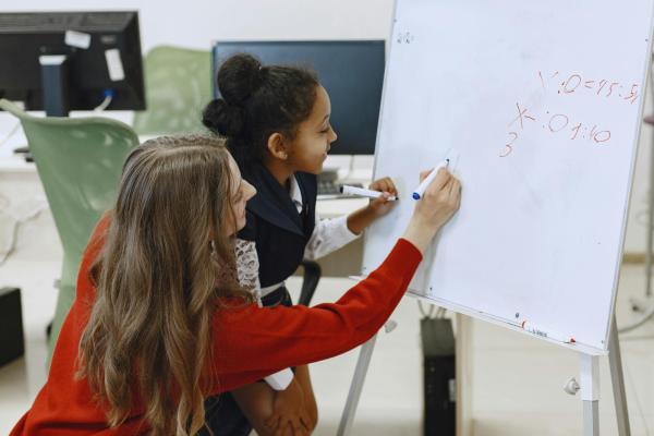 A teacher and student doing maths on a whiteboard