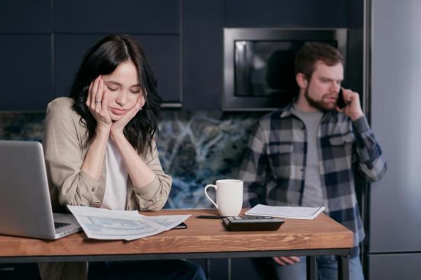 Woman stressing about bills while man stands in the background