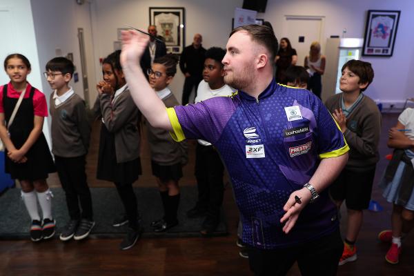 Darts player Luke Littler preparing to throw a dart