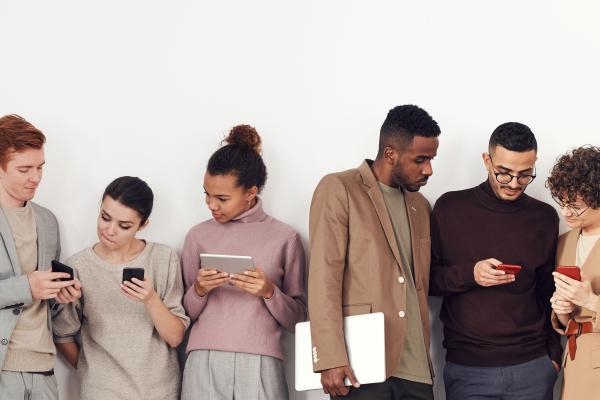 A line of six people all looking at mobile phones