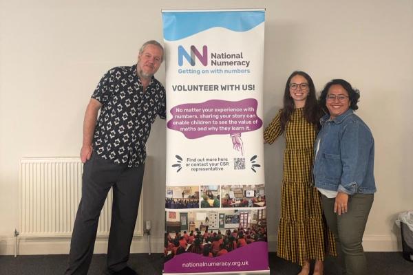 National Numeracy staff standing next to a National Numeracy banner and smiling