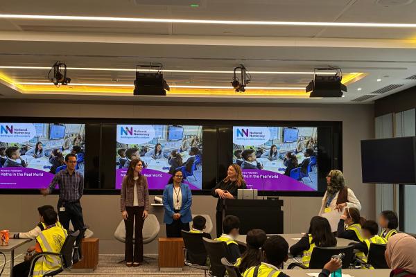 A group of school pupils listening to corporate volunteers talking abut numeracy in the workplace