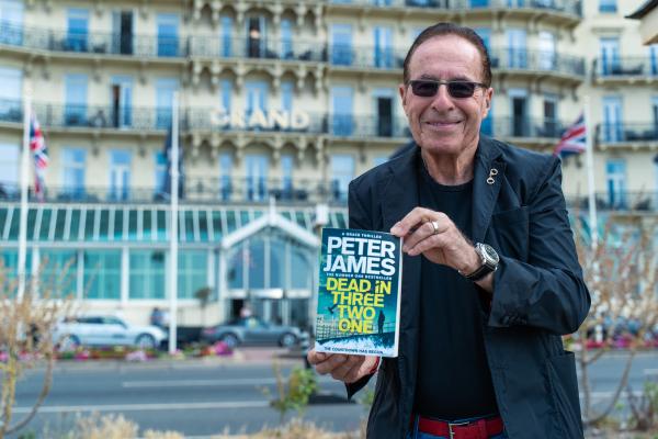 Author Peter James holding a copy of his book, Dead in Three Two One