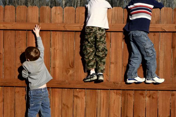 Three children looking over a fence - one needs a leg up